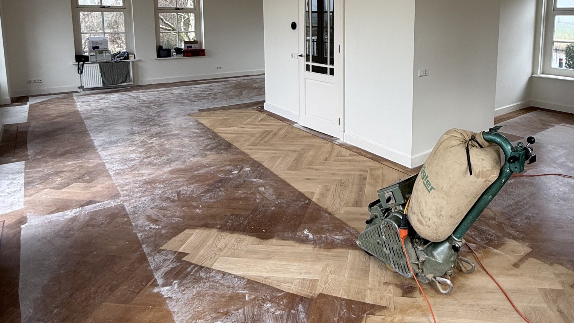 Houten vloer schuren Professioneel schuren van een houten visgraatvloer door Themen Floors Amsterdam tijdens vloerrenovatie.